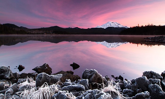 Landscape photo of a snowy mountain at sunset in purple hues