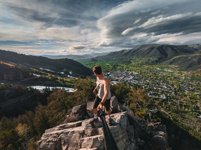 A man on a mountain taking a picture of himself with a selfie stick 