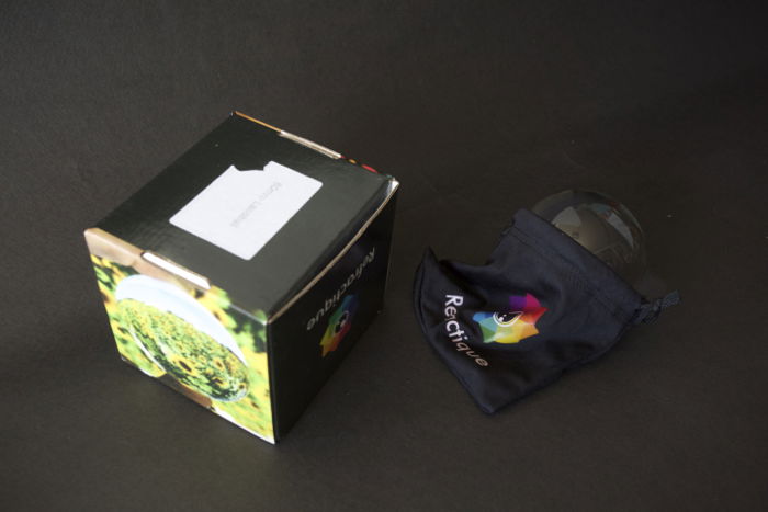 Lensballs with its Refractique logo in a case beside its packaging