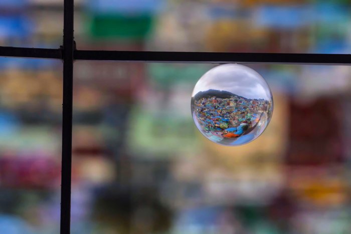 a crystal ball in a window frame reflecting a sprawling cityscape