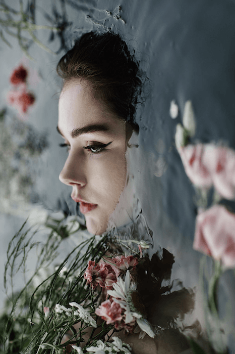 surreal portrait photography of a woman in water surrounded by flowers