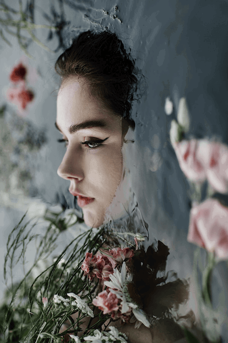 surreal portrait photography of a woman in water surrounded by flowers