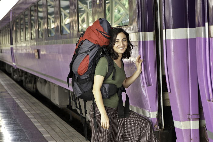 Photo of a backpacker standing next to a train