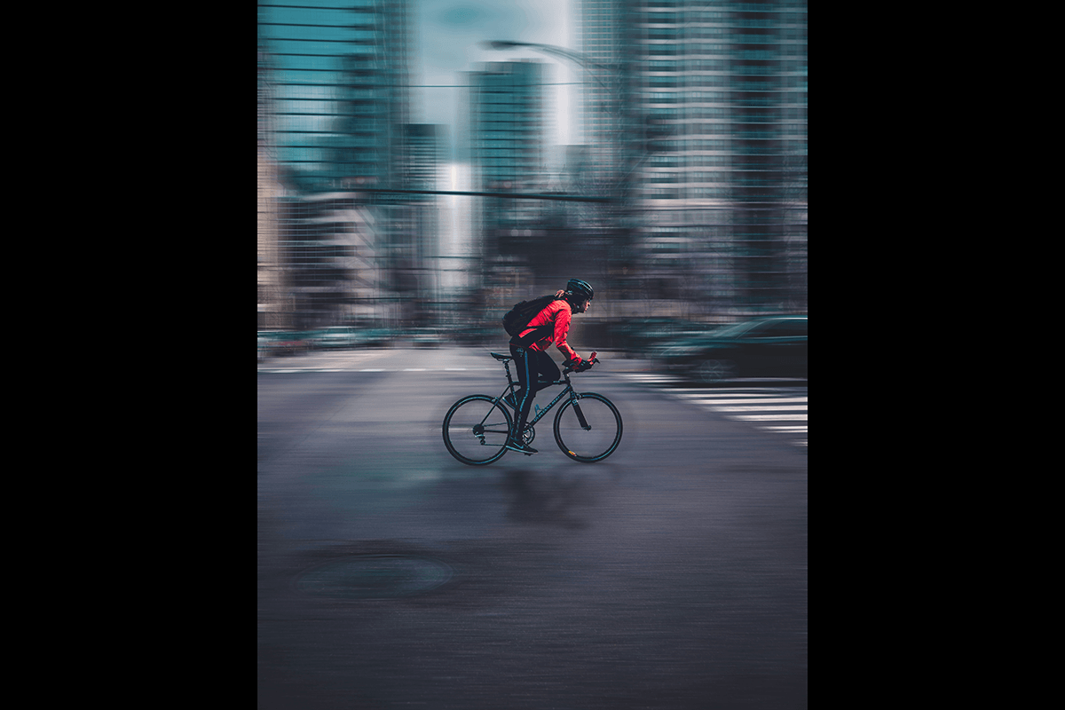 A bike courier speeding across a city street as an example of cycling photography