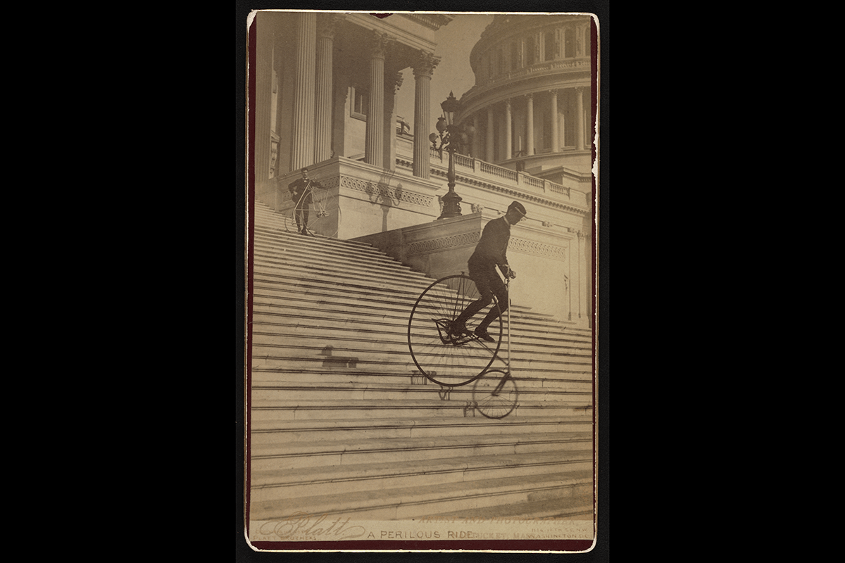 A photo from the 1800's of a man on a bike riding down the steps of Capitol Hill
