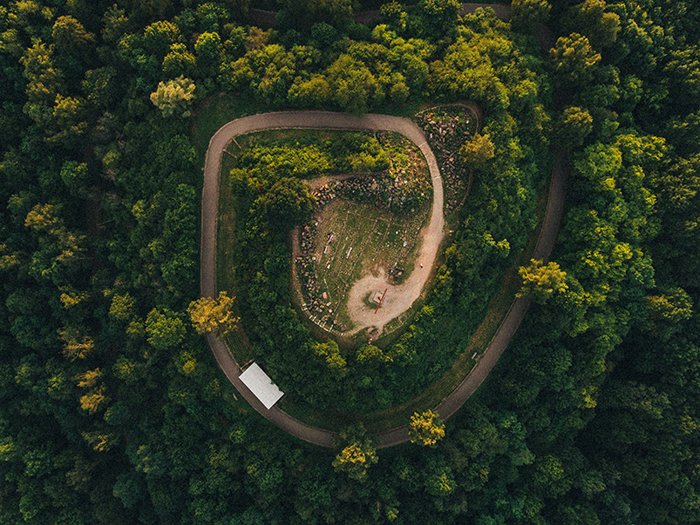 A drone photo of a forest and a spiral-like road