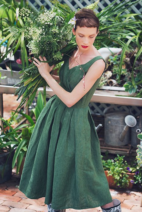Photo of a model dressed in green holding plants