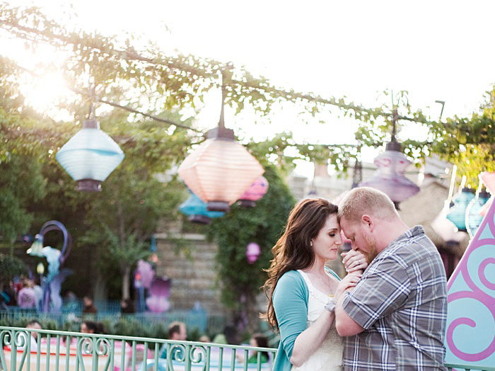 A couple kissing each others hands surrounded by lanterns highlighting engagement photo poses