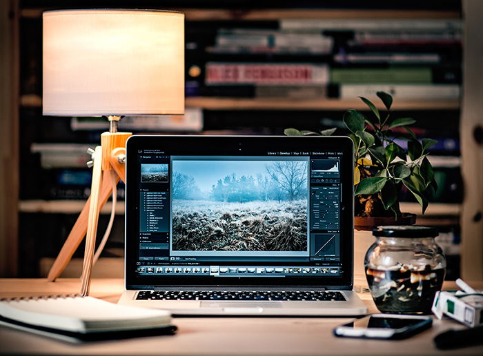 Photo of a laptop on a desk with a lamp behind it