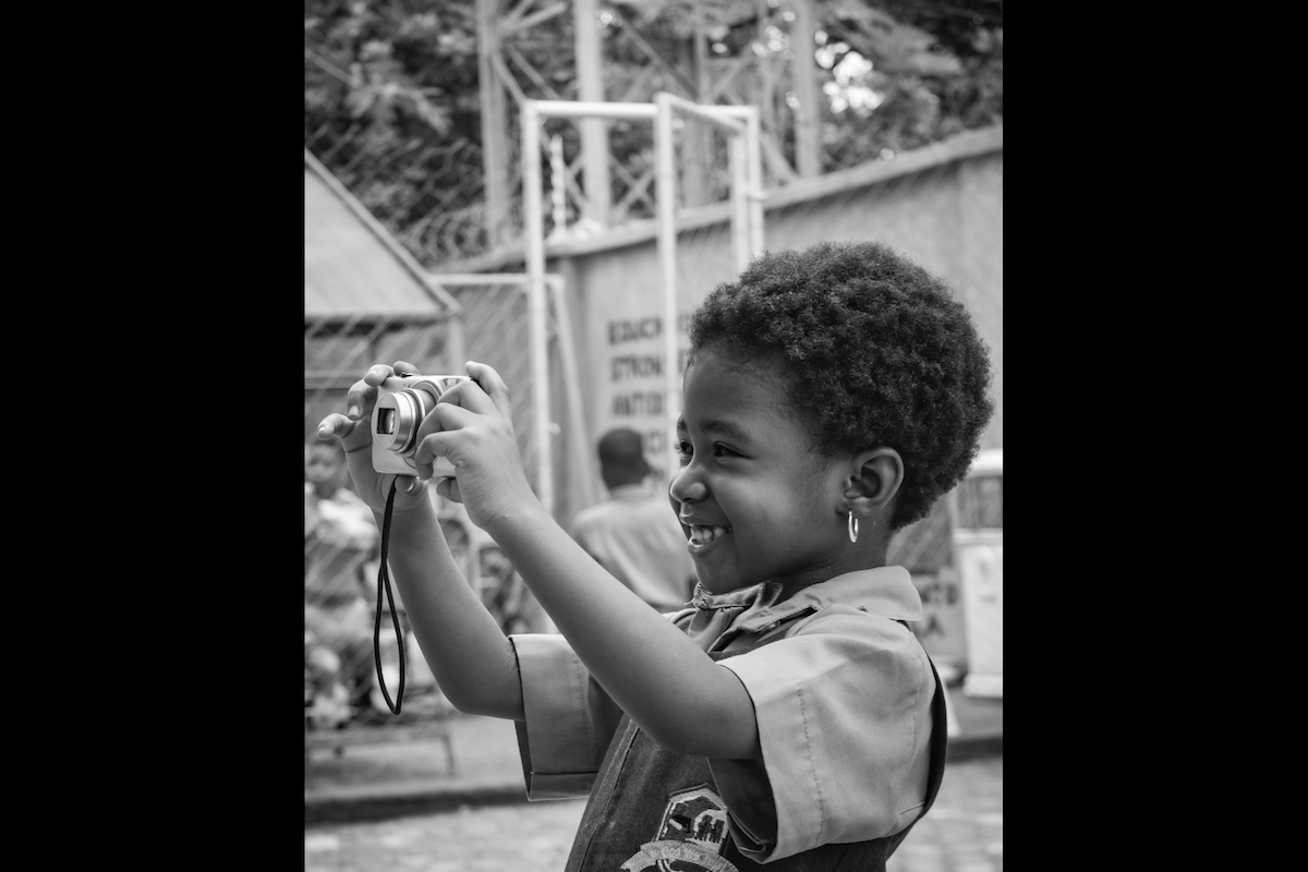 A child holding up a point-and-shoot camera to take a picture to show photography for kids