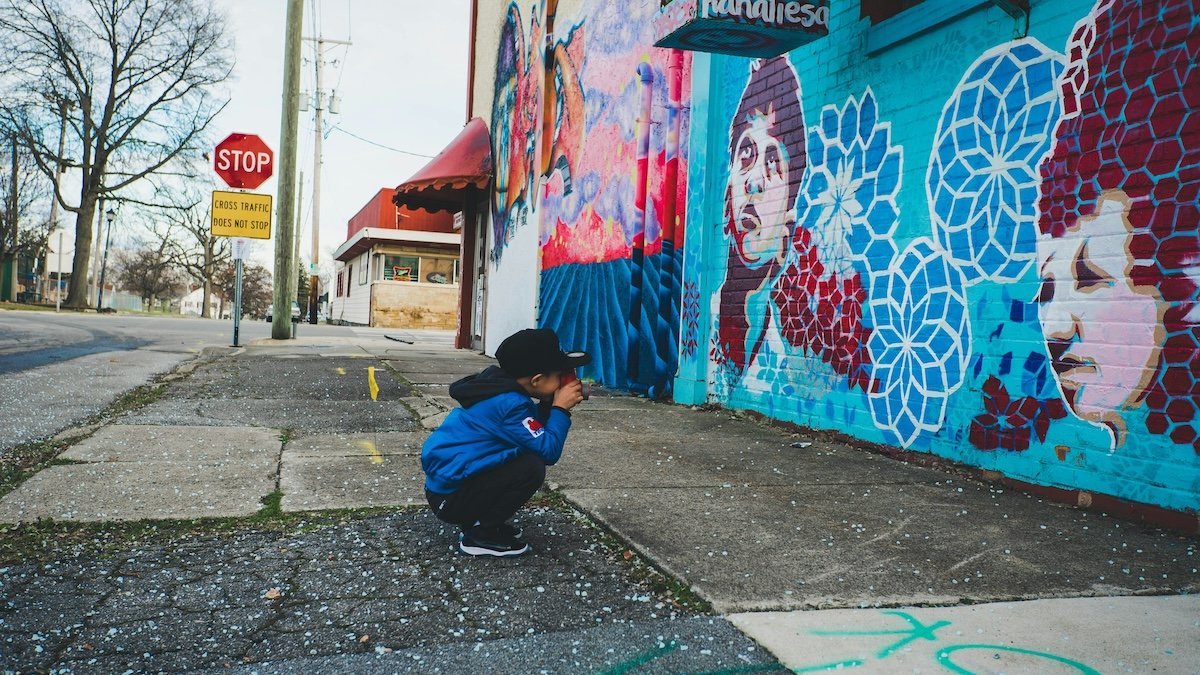 A child crouching to take a picture of a street mural to show photography for kids