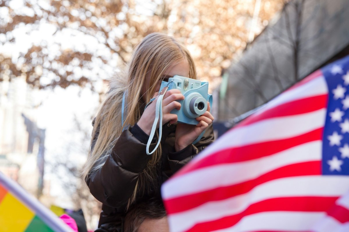 A girl taking a picture with an instant camera to show photography for kids