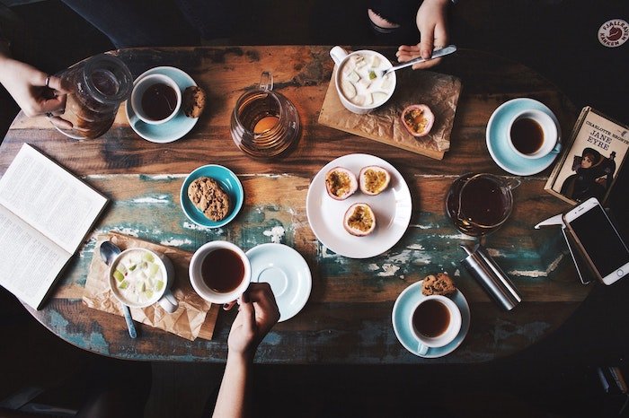 Coffee cups and food laid out on a wooden table 