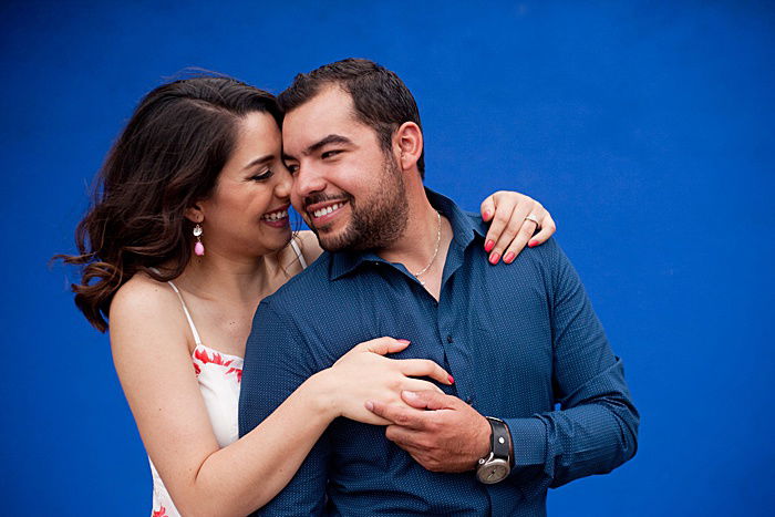 a romantic portrait of a couple trying engagement photo poses against a blue background