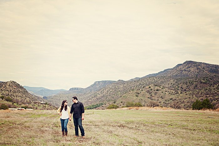 a romantic portrait of a couple trying engagement photo poses in a scenic landscape