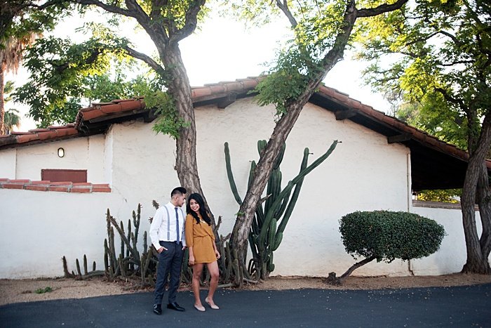 Young couple standing in front of a building with cacti 
