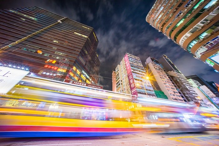 A blurry train speeding by with city buildings towering above for time-lapse photography