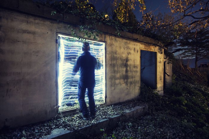 urbex photography: cool backlighting behind a man exploring an abandoned building