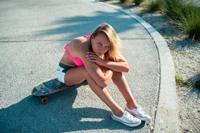 outdoor portrait of a female model sitting on a skateboard