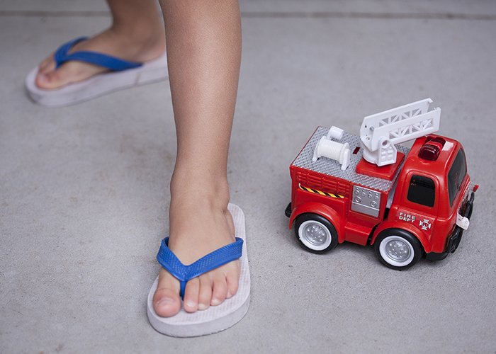 a close up of a childs feet beside a toy truck