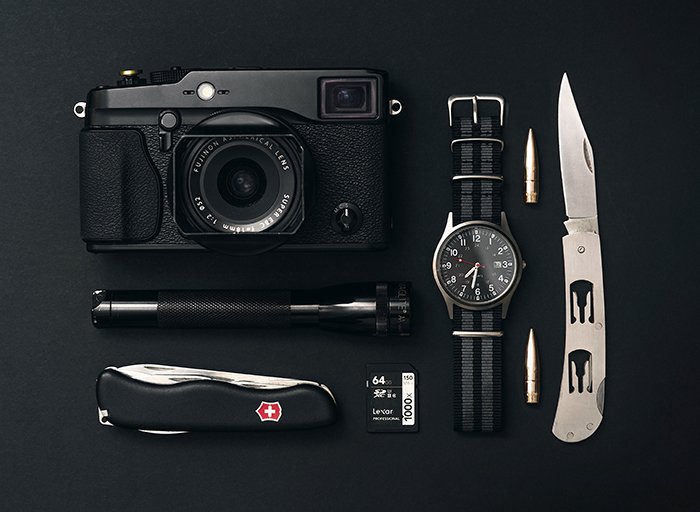 Product photo of a camera, a watch, and pocket knives