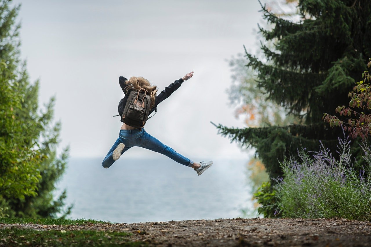 An action photo of a person jumping in the air outside with trees and bushes around them