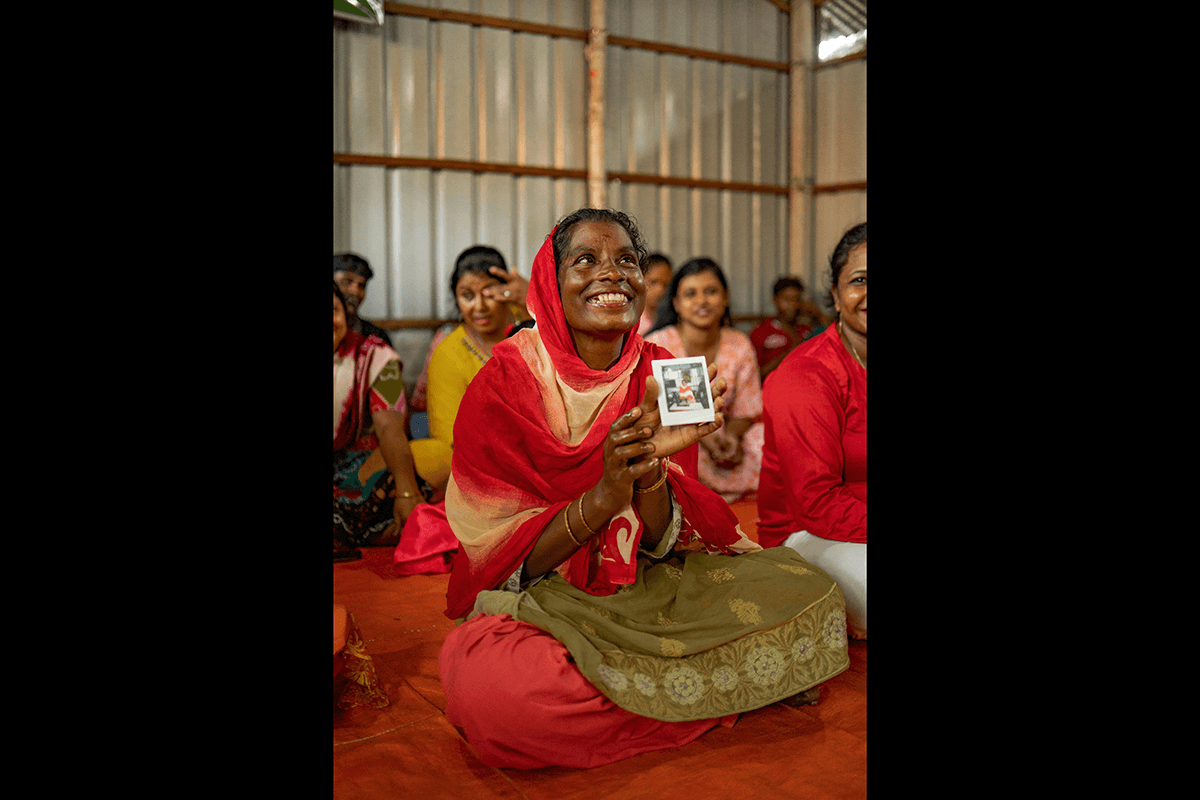 A photo of a woman smiling holding up a polaroid of herself as an example of photography style