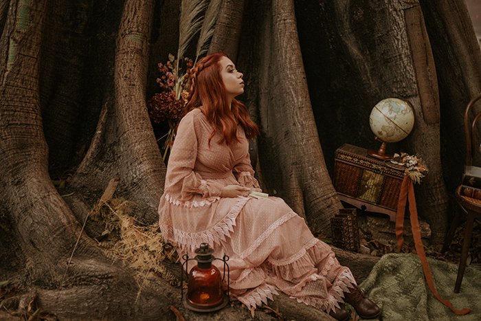 conceptual fantasy themed portrait of a female sitting in the woods