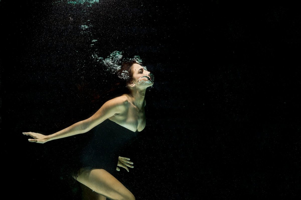 An underwater portrait of a woman with air bubbles coming out of her mouth as an example of photography style
