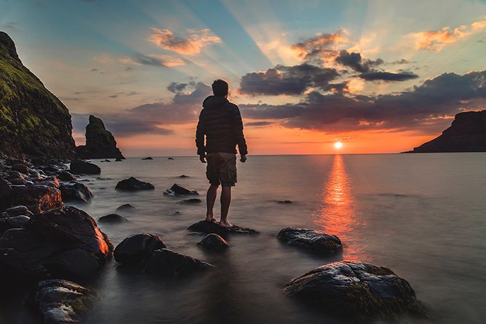 A man watching a sunset on a rocky beach