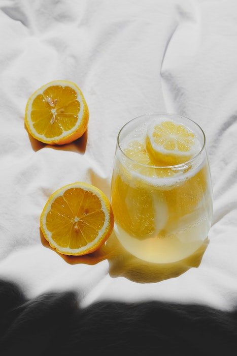 A small glass of lemonade with lemon slices on a white blanket