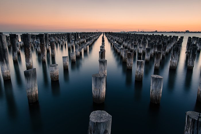 wooden poles in water at sunset