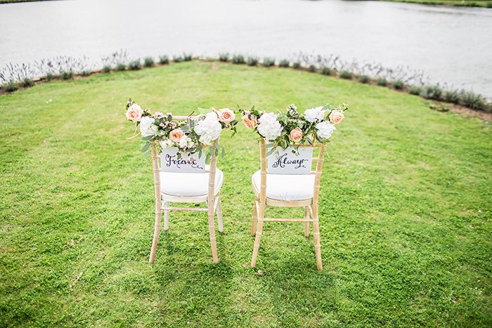 Two chairs on a river bank decorated for the bride and groom 