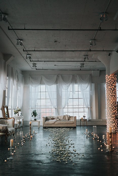 A path of petals and candles leading to a sofa in a loft 