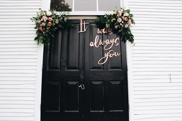 a door decorated with flowers and lettering as wedding photography props