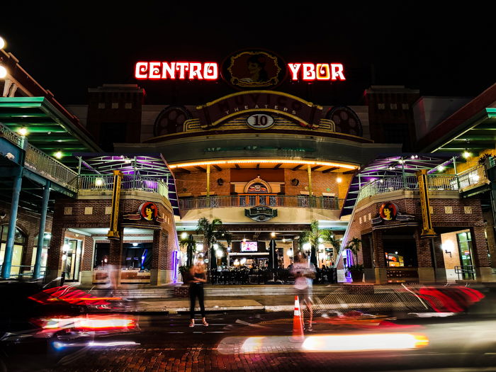 Photo of a building at night with moving cars in the foreground