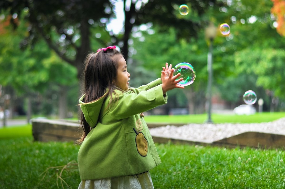 A child catching a bubble in a park as a kids photo pose
