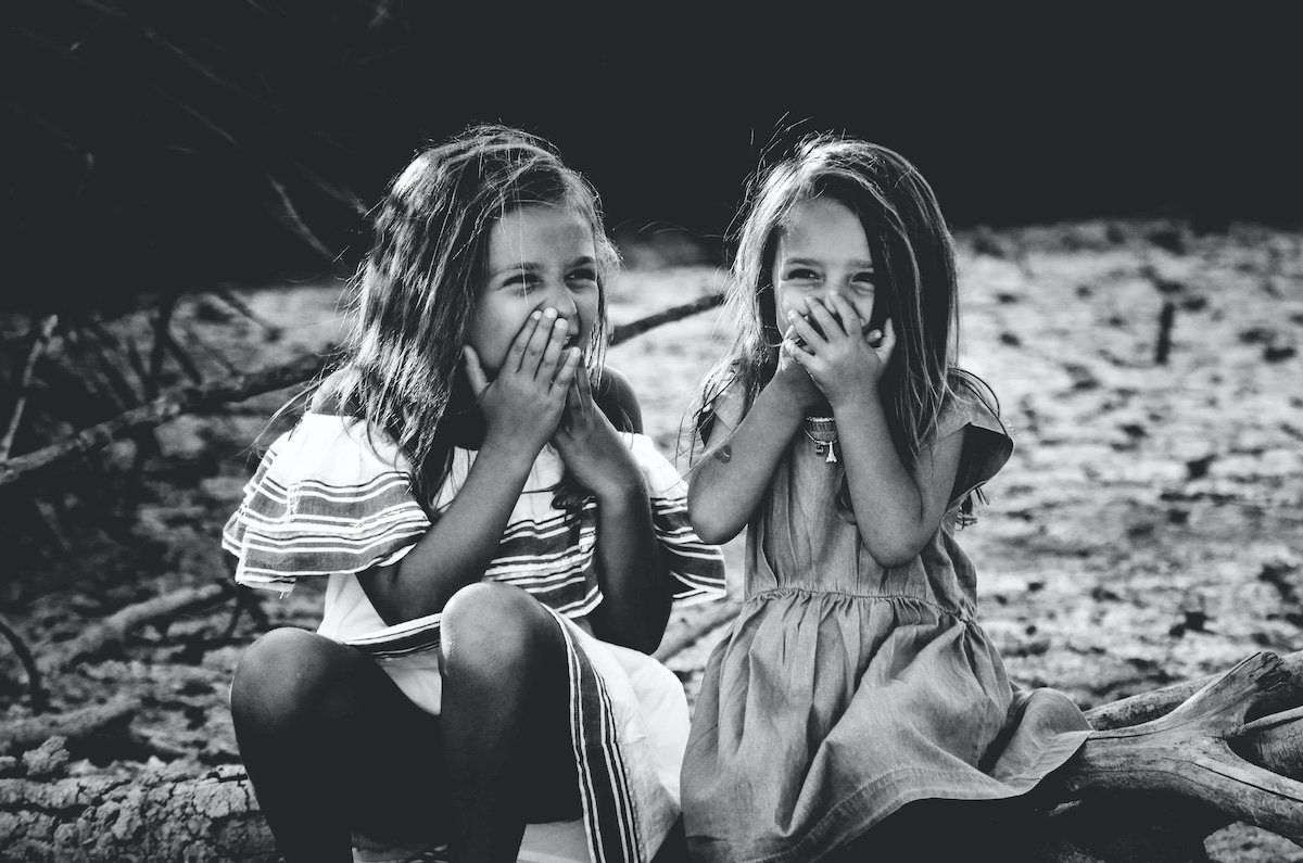 Black-and-white photo of two girls laughing for a kids photo pose