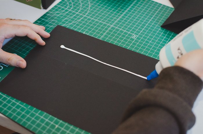 A person gluing black paper to make a DIY projector