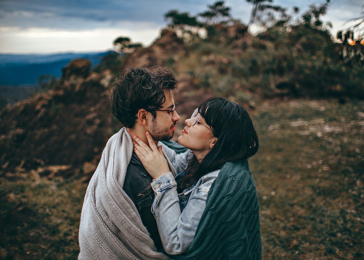 Two people in an embrace standing under a blanket outside for couple poses