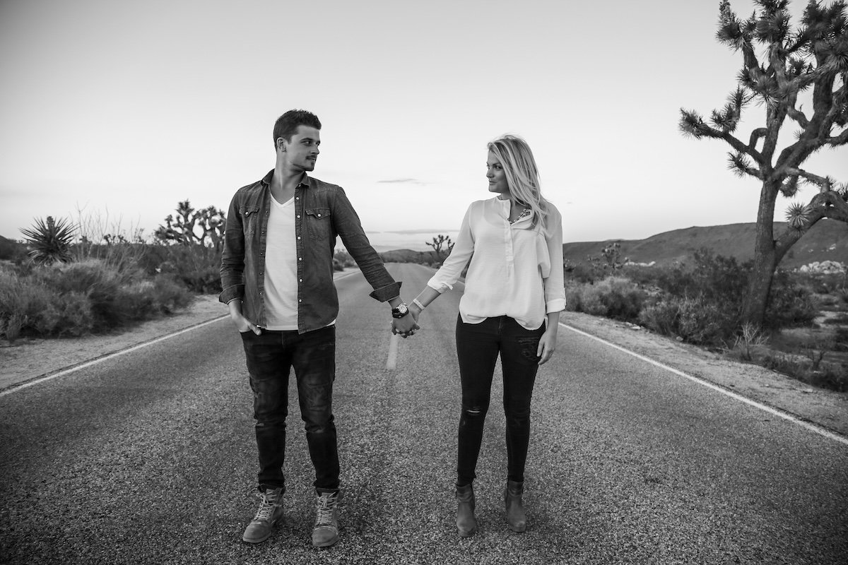 Black-and-white photo of a couple holding hands and looking at each other for couple poses