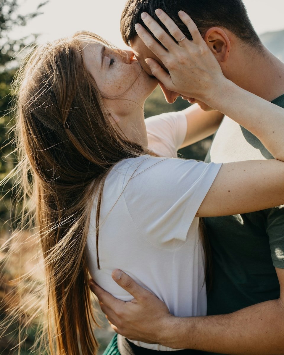 A woman kissing a man on the forehead for couple poses