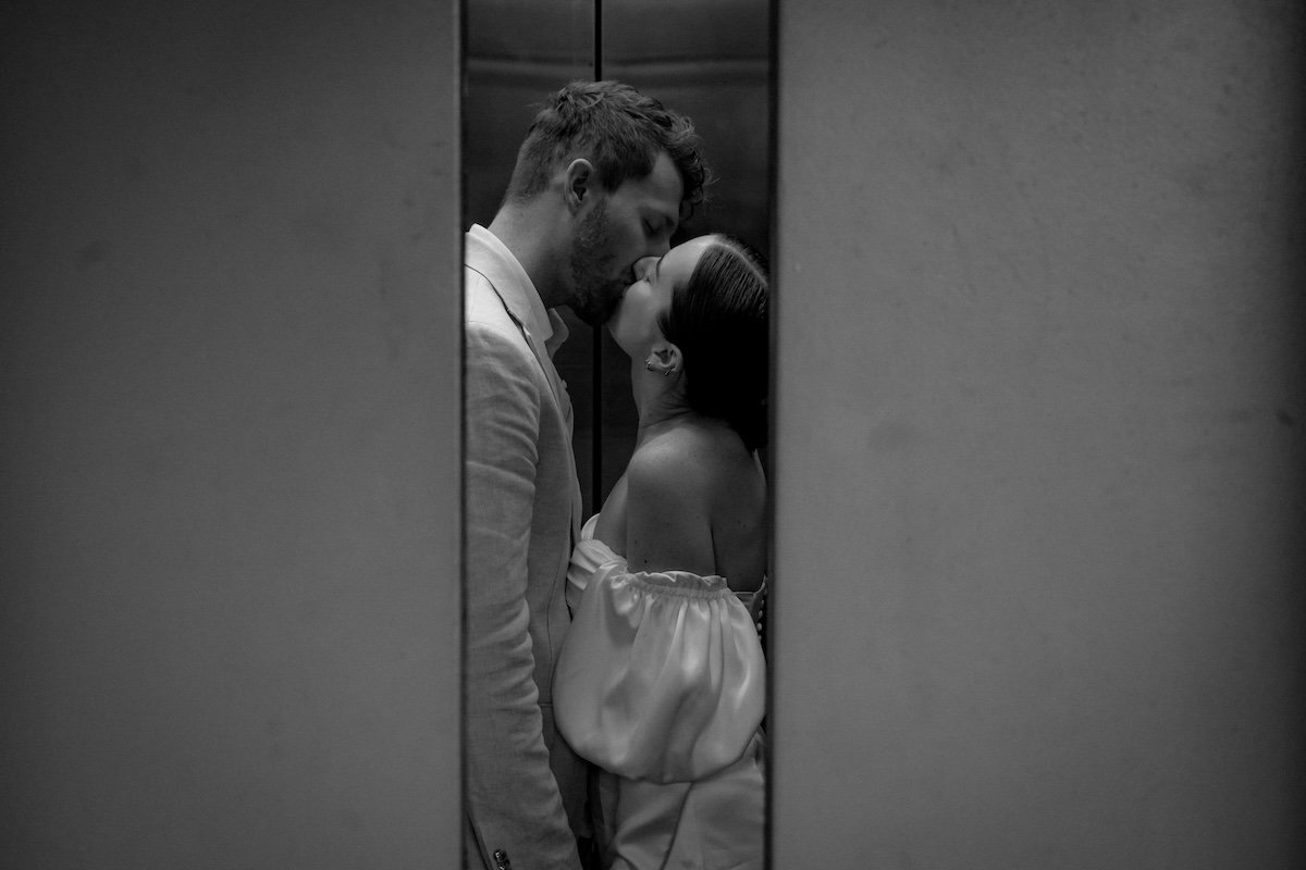 Two people kissing with an elevator closing for couple poses