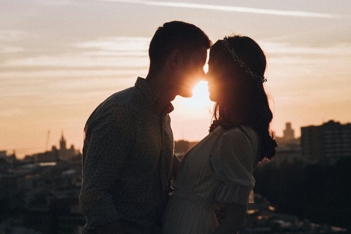 Two people leaning in for a kiss at sunset for couple poses