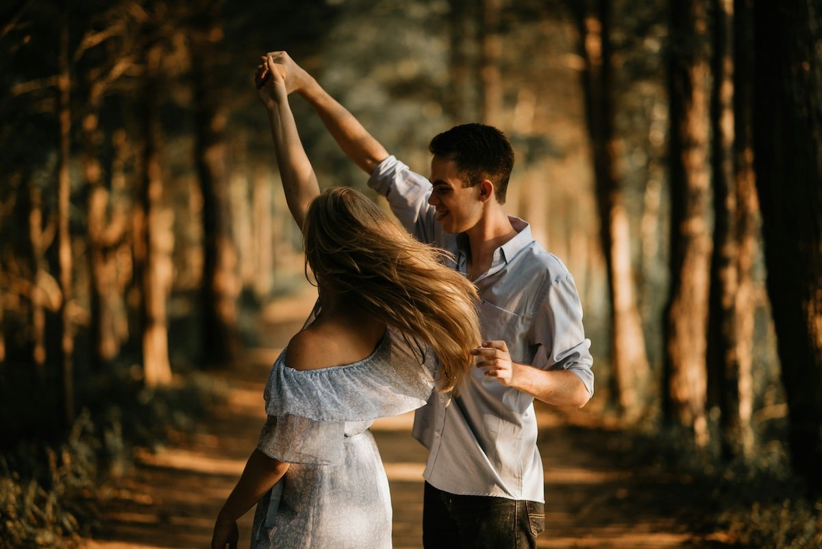 A man having a woman twirl in the woods for couple poses