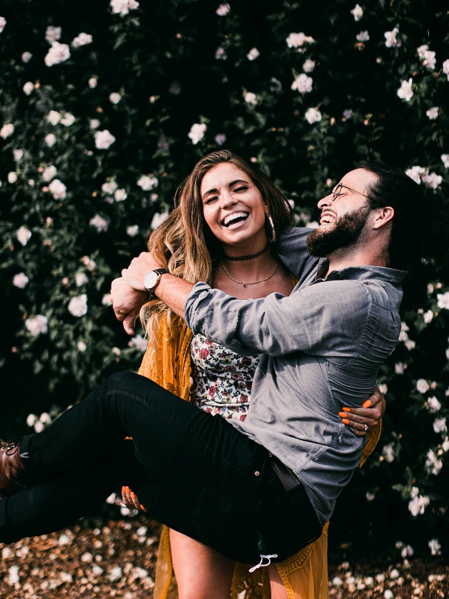 A woman picking up a man with both of them laughing for couple poses