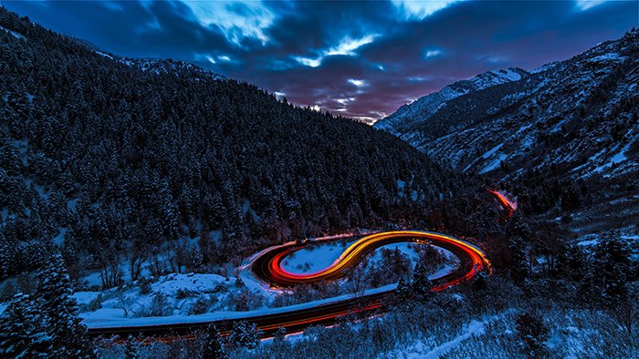Mountainous landscape with colorful light trails of passing cars shot with long exposure 