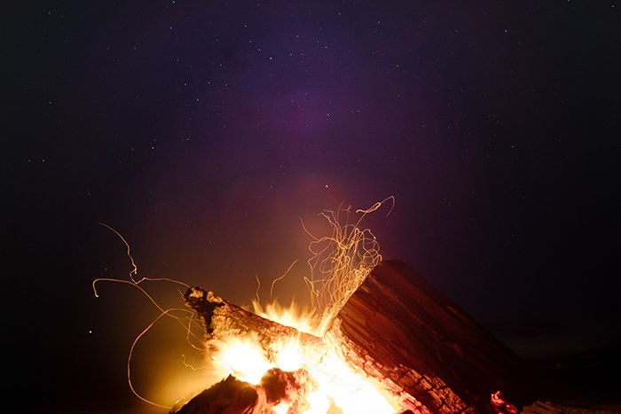 A campfire outdoors under the night sky
