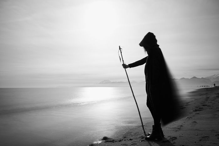 A hooded figure standing on a beach