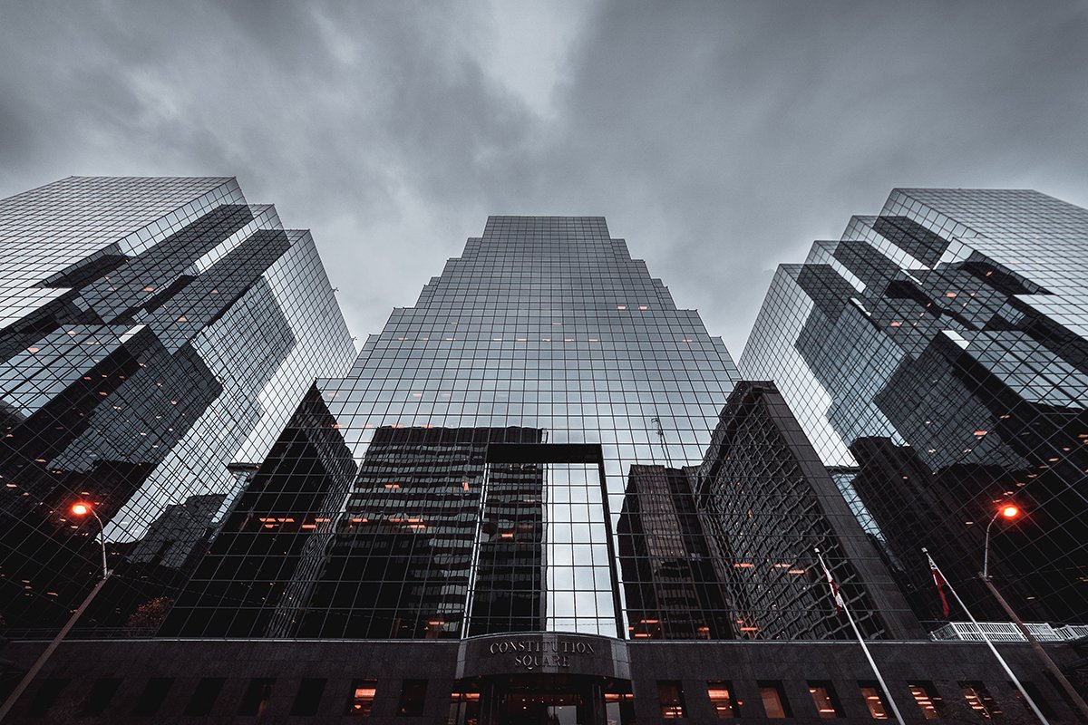 Modern glass buildings rising up in a cloudy sky